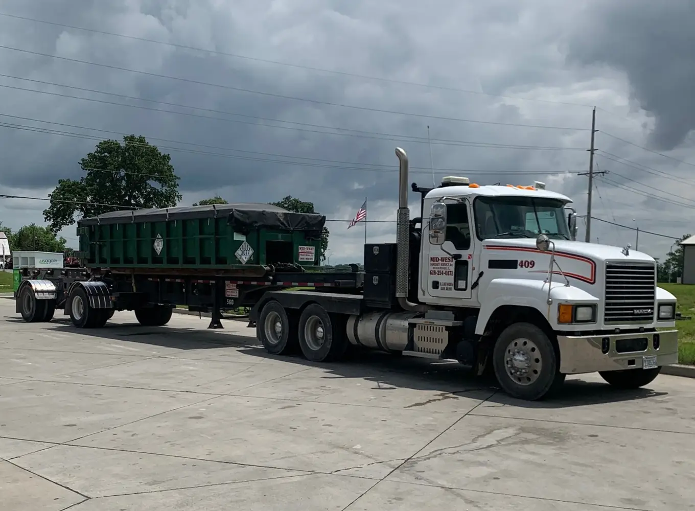 Midwest Sanitary Services truck carrying a sealed roll-off dumpster in the wood river il area